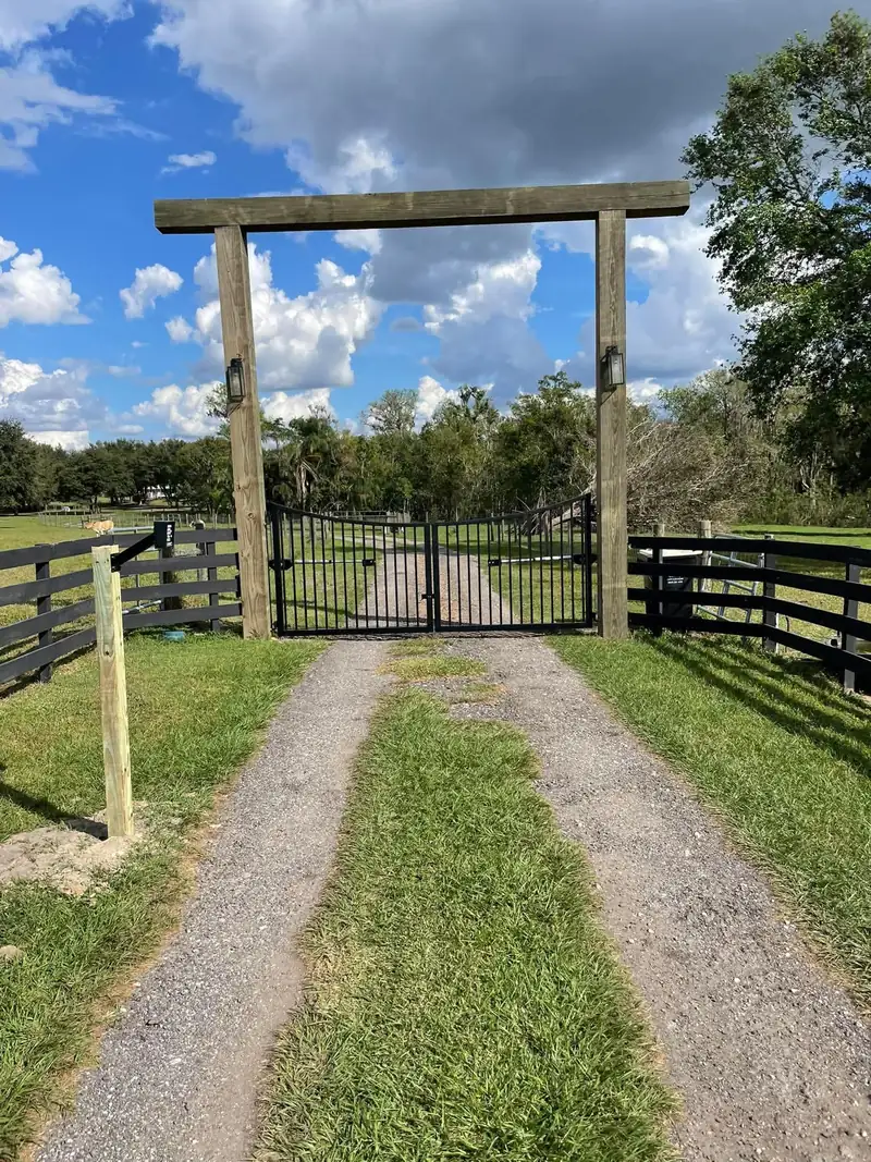 Timber posts and crossbeam with lanterns framing a black double gate