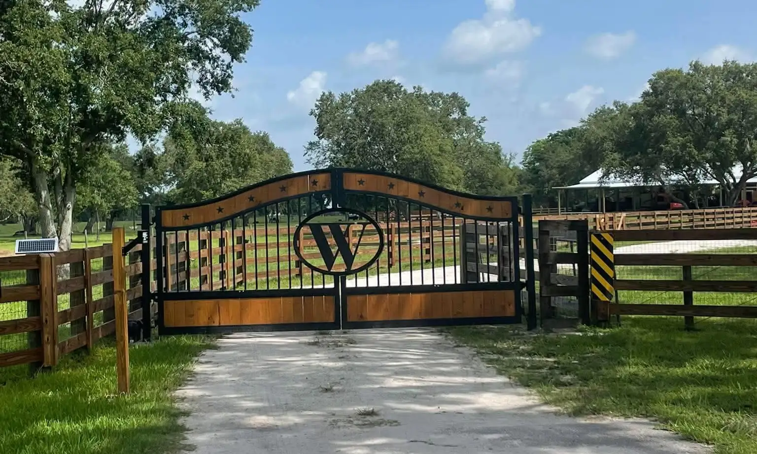 Custom double driveway gate with wood panels, stars and a W monogram